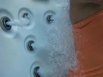 Water flowing from several jets beside a seated hot tub user